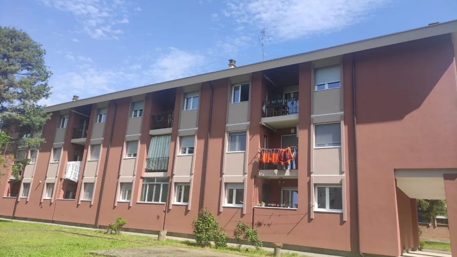 Edificio basso con facciata rosa, finestre e prato antistante