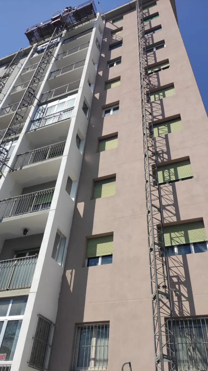 Facciata rosa di un condominio con piattaforma di lavoro in quota