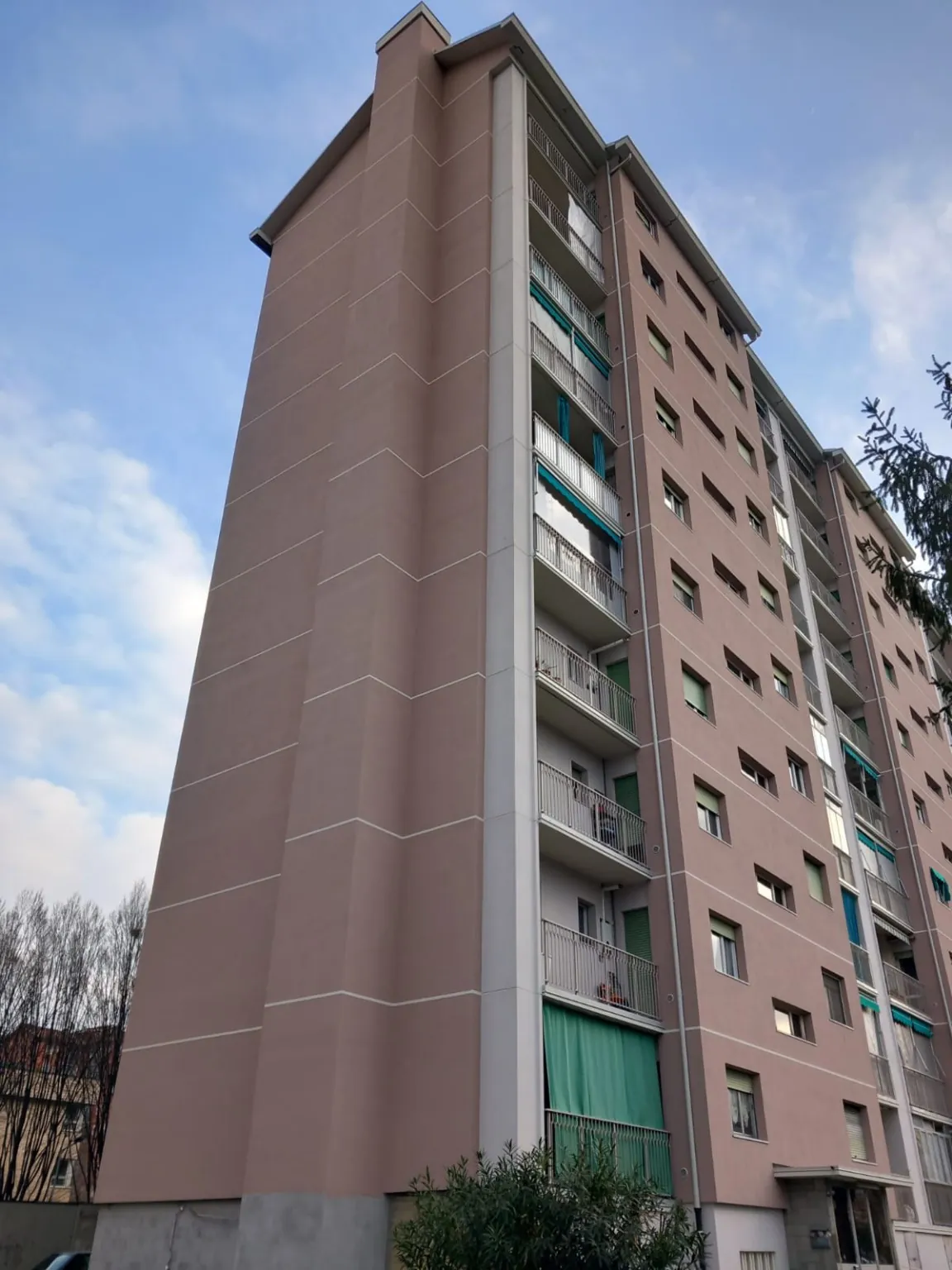 Facciata rosa di un edificio residenziale con balconi, vista dal basso